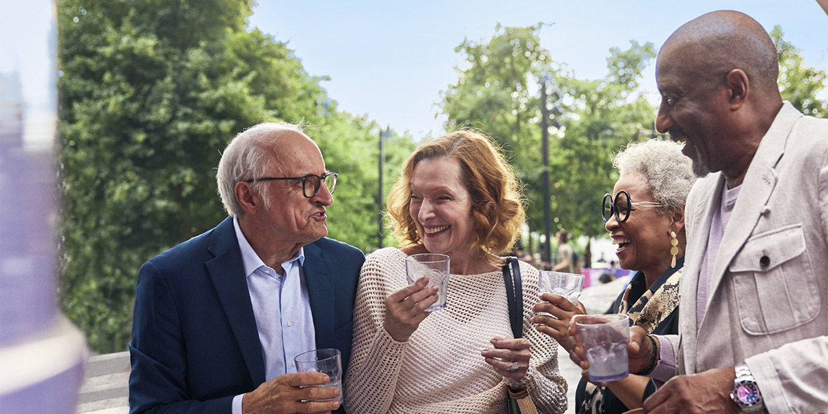 Senior living residents socializing with rocks glasses while talking and laughing