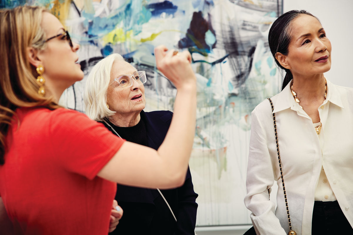 Three women admire work in an art gallery