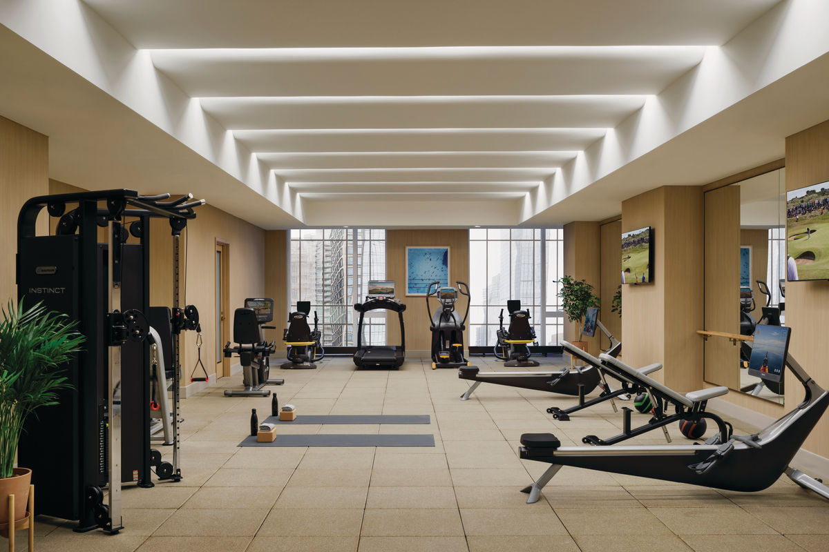 An exercise room with treadmills, rowing machines, and weight benches