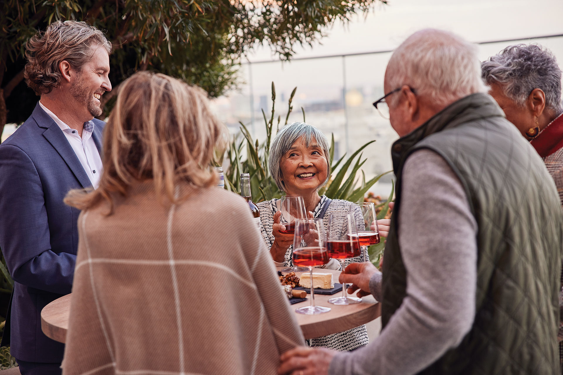 A smiling group of seniors enjoy wine and conversation