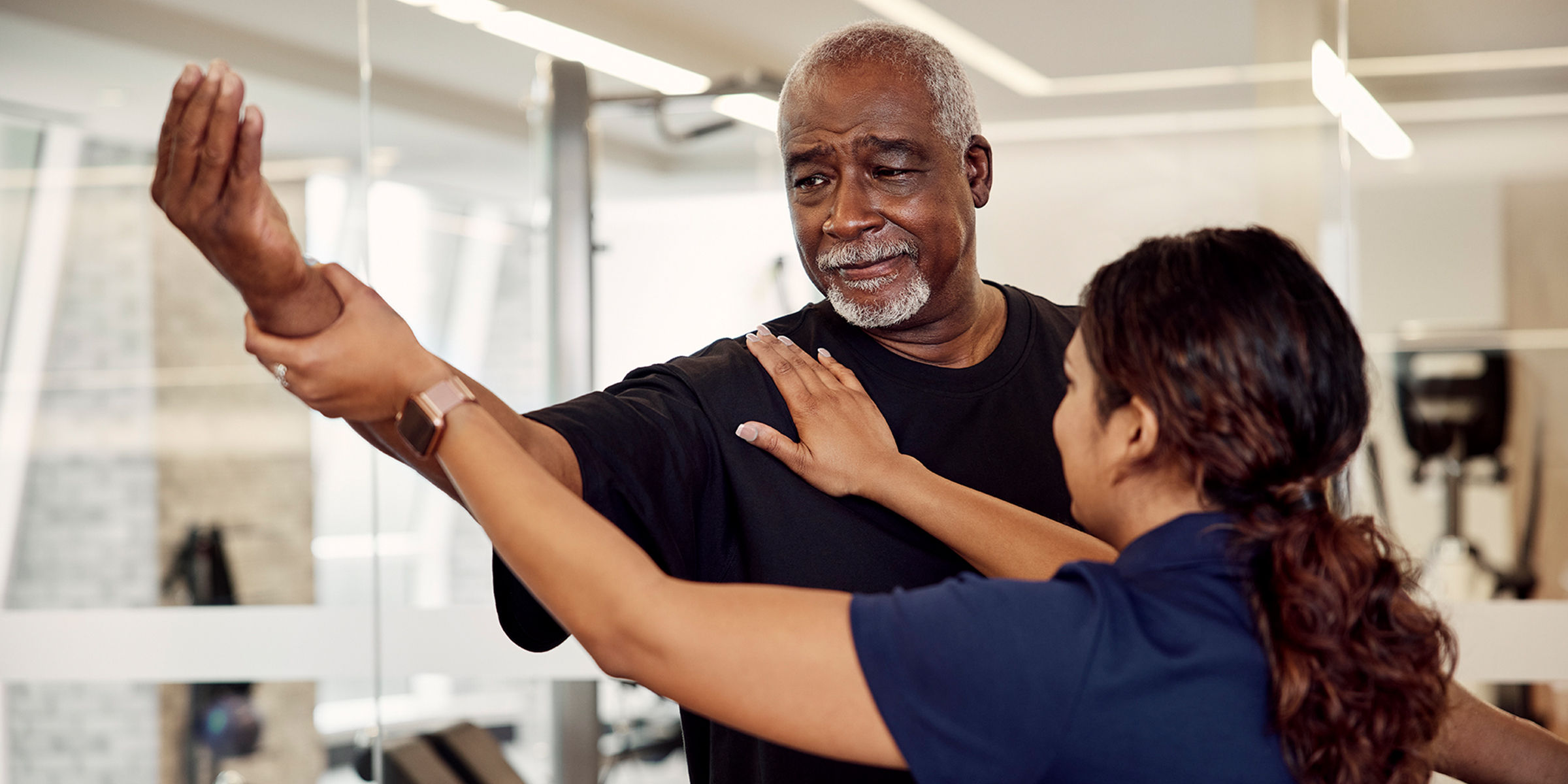 Senior man expanding the range of motion of his arm with the help of a wellness guide
