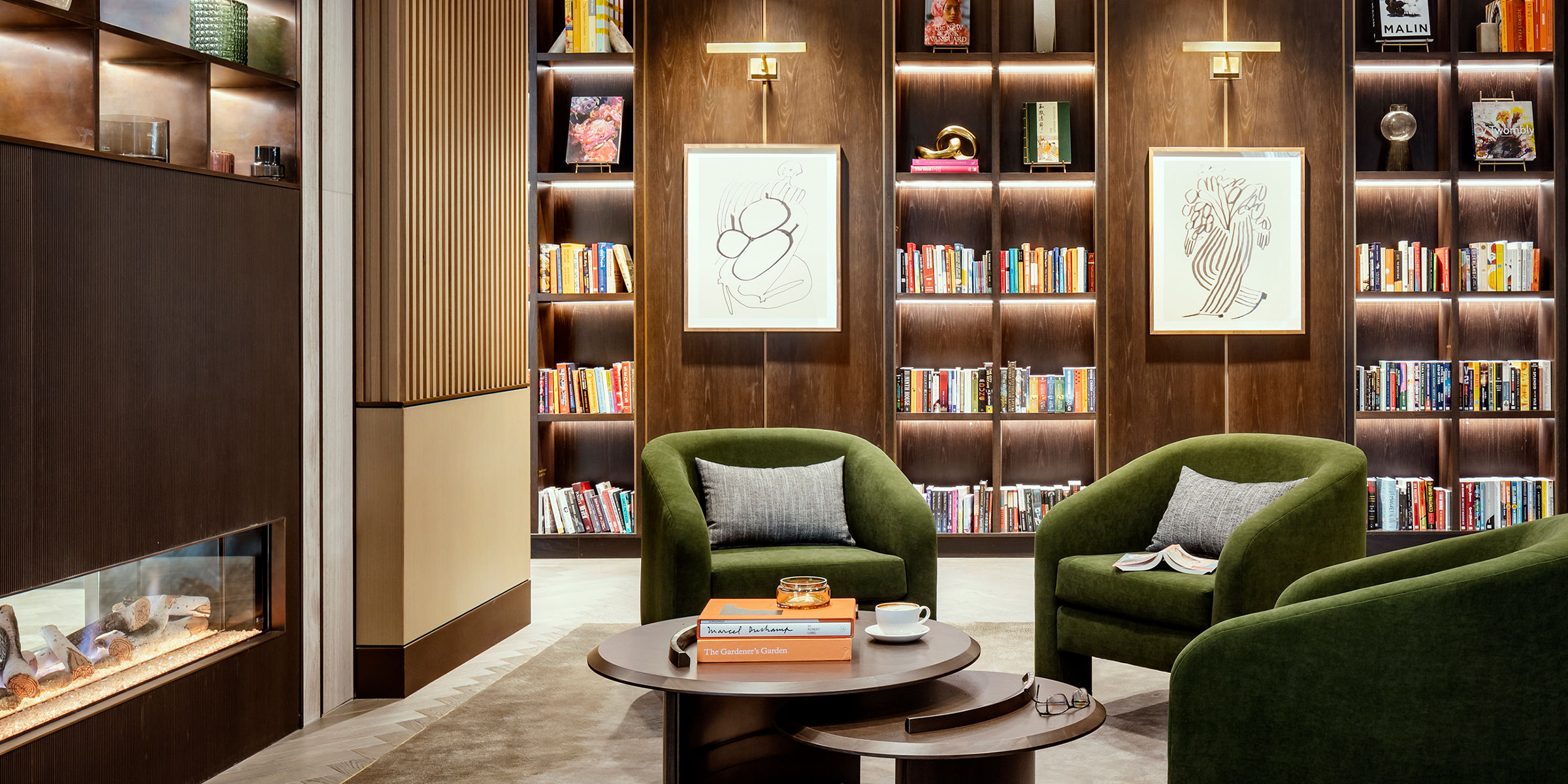 Coterie's modern library with comfortable seating, lit-up bookshelves, and modern abstract art on the walls.
