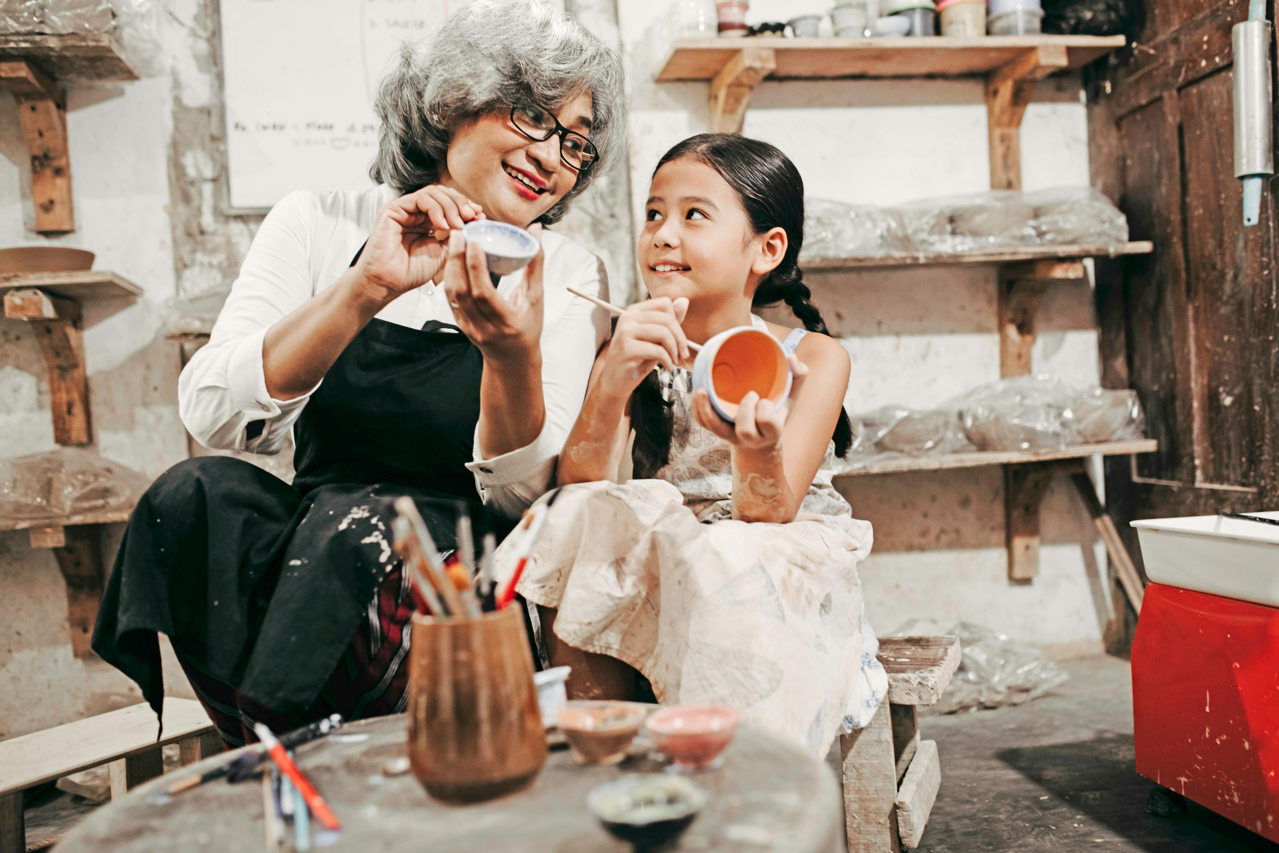 A woman and her granddaughter paint pottery together