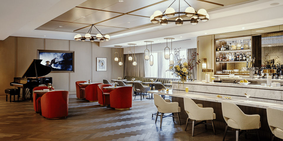 Coterie Senior Living lounge area, includes grand piano, multiple seating areas and a white marble bar.